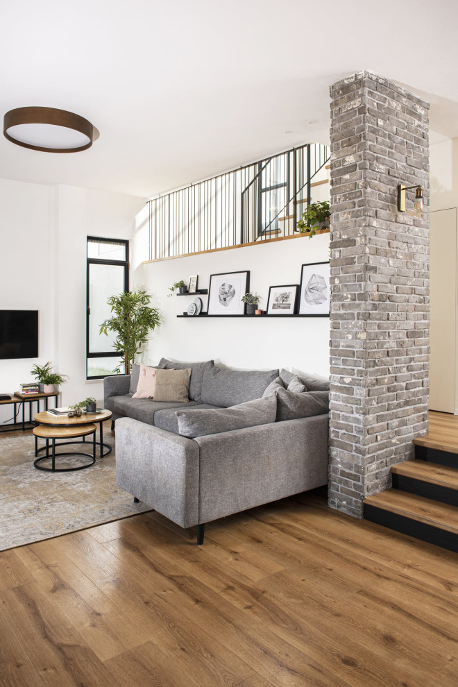 Imagen de salón abierto tradicional renovado de tamaño medio con paredes blancas, suelo de madera en tonos medios y televisor colgado en la pared