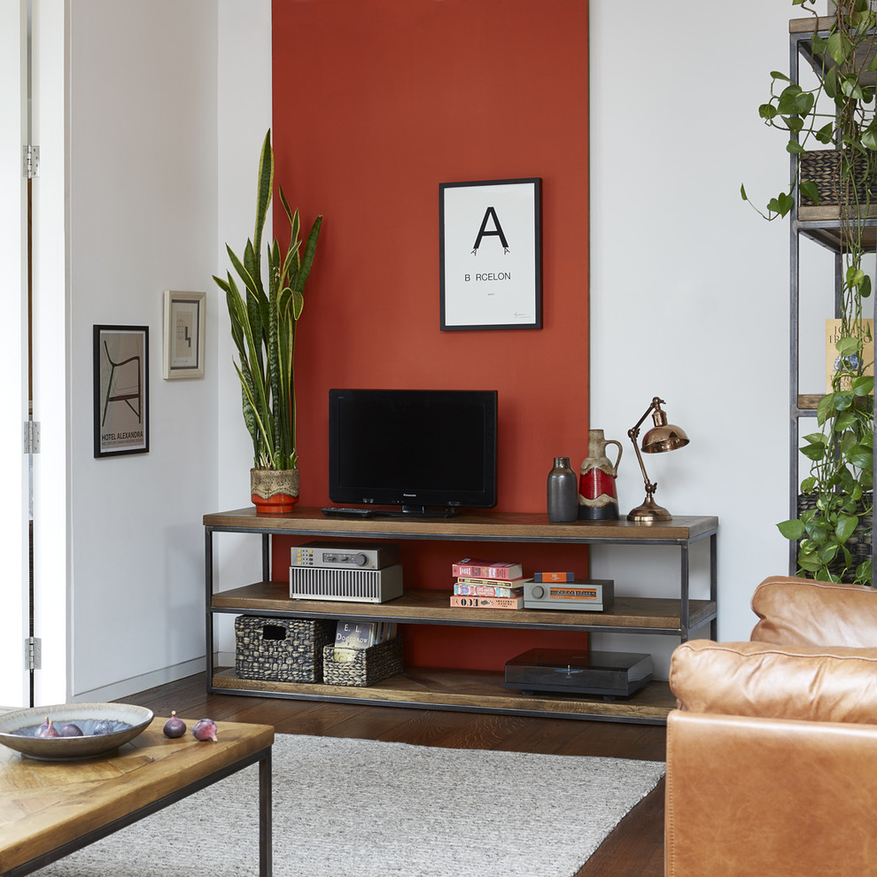Aménagement d'un petit salon industriel ouvert avec parquet foncé, un mur rouge et un téléviseur encastré.
