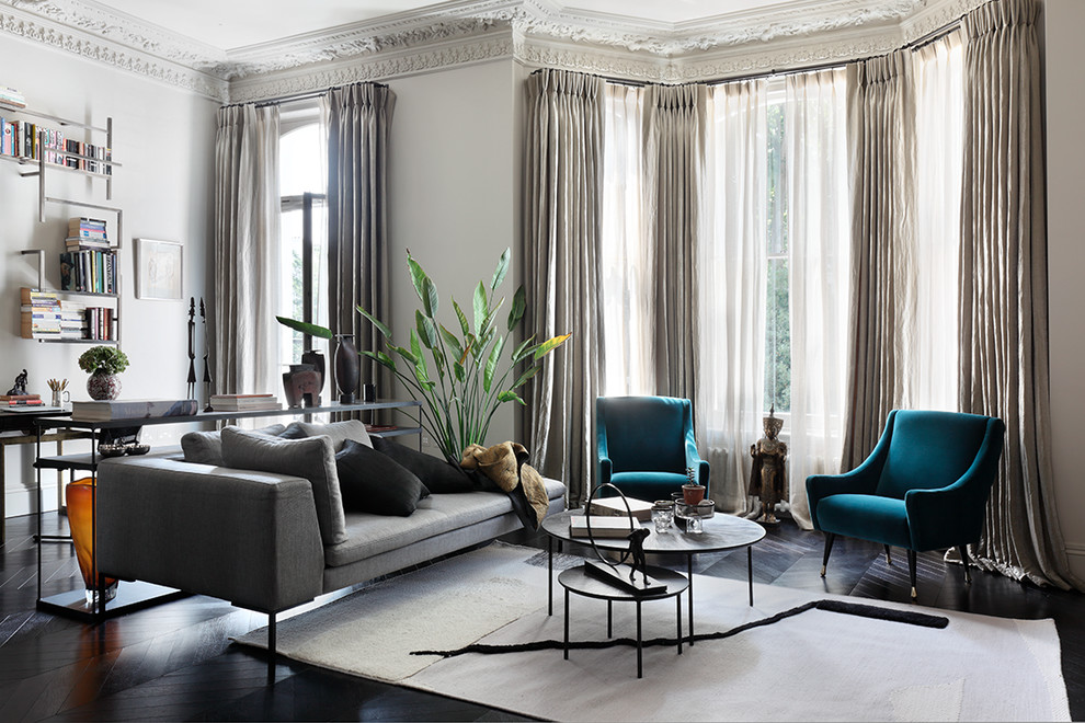 This is an example of a classic grey and teal living room in London with beige walls, dark hardwood flooring and black floors.