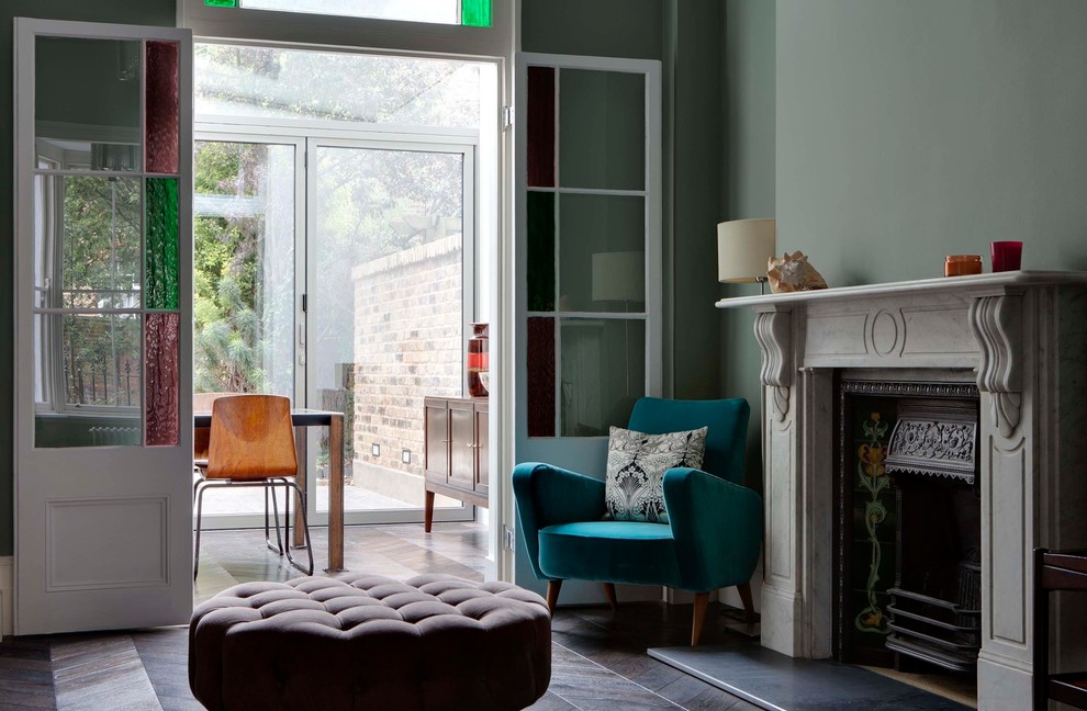 Mittelgroßes, Repräsentatives, Fernseherloses, Offenes Wohnzimmer mit grüner Wandfarbe, dunklem Holzboden, Kamin und Kaminumrandung aus Stein in London