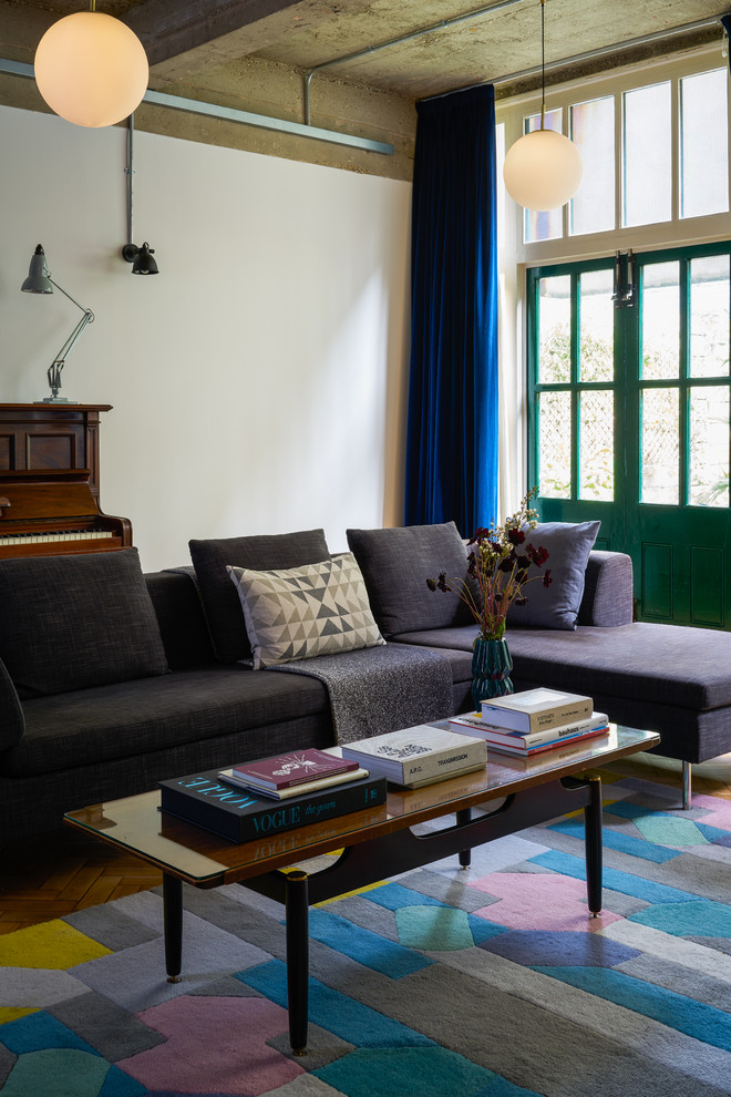 This is an example of an eclectic living room in London with white walls and brown floors.