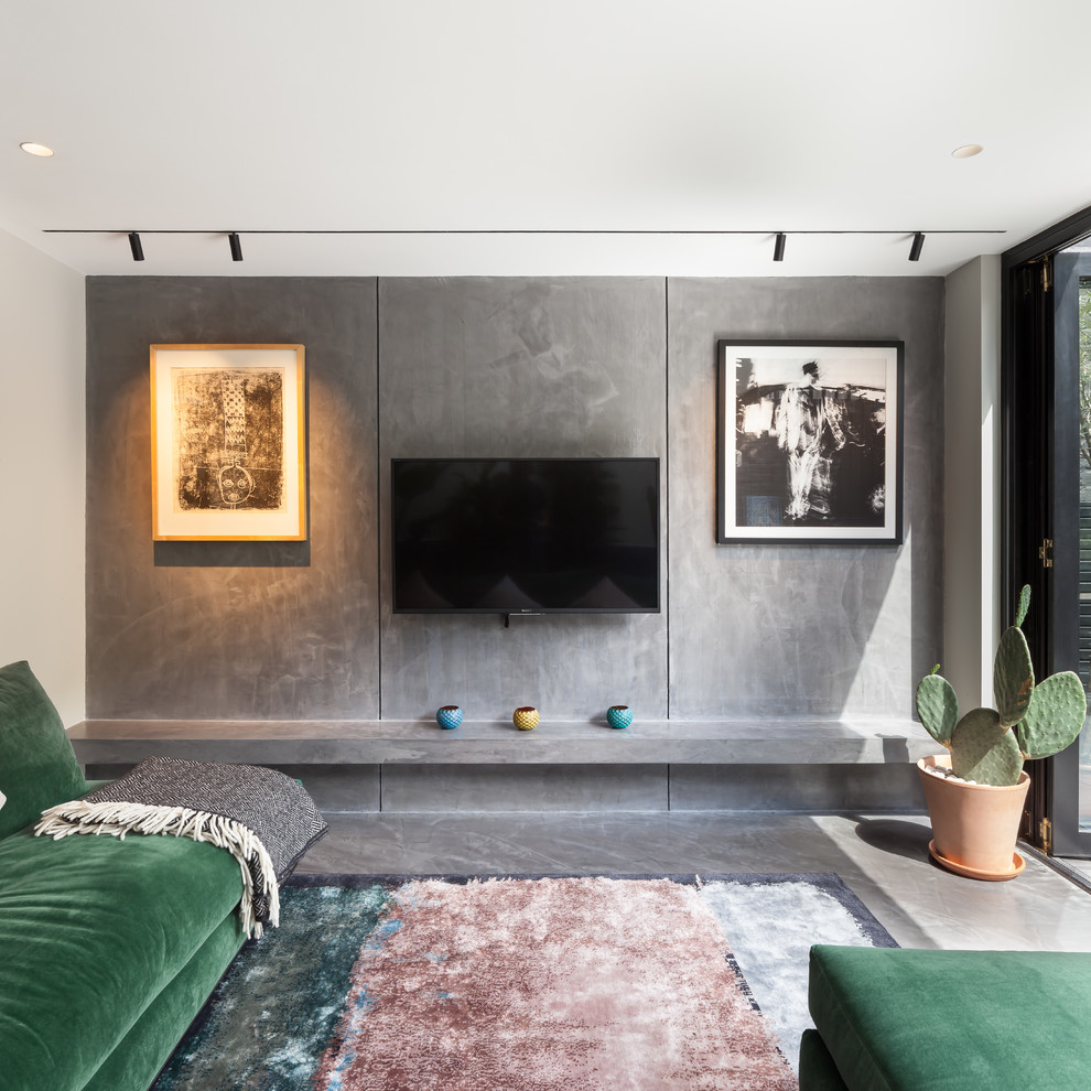 Esempio di un soggiorno contemporaneo di medie dimensioni e aperto con pareti grigie, pavimento in cemento, TV a parete e pavimento grigio