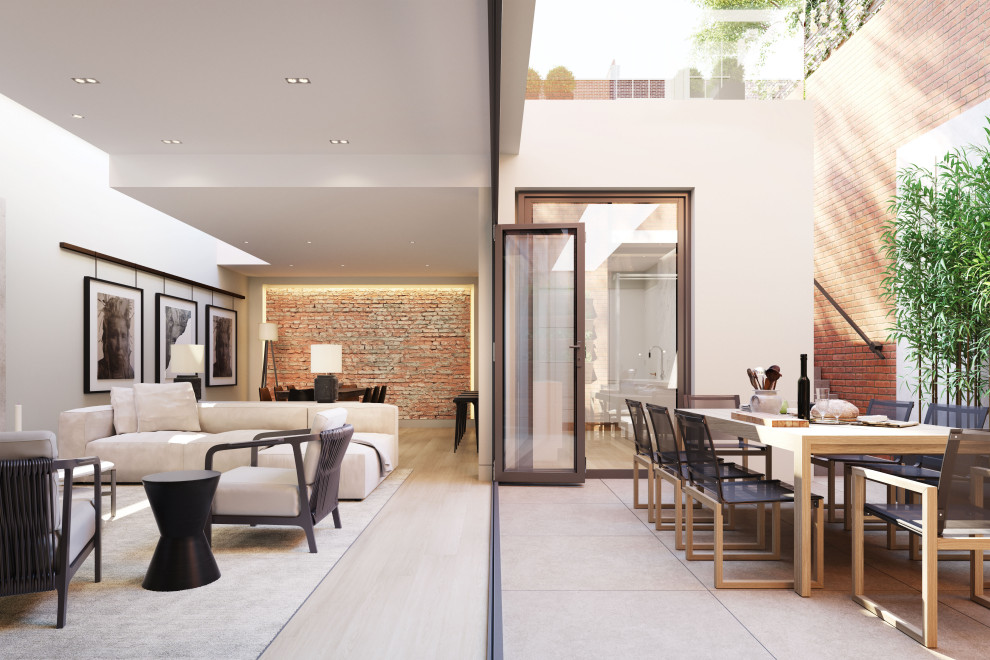 Modelo de salón abierto minimalista grande sin chimenea con paredes beige, suelo de madera clara, televisor colgado en la pared, suelo beige, bandeja y ladrillo