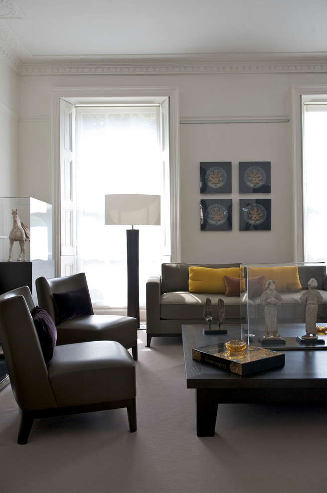 This is an example of a medium sized contemporary enclosed living room in London with white walls and carpet.