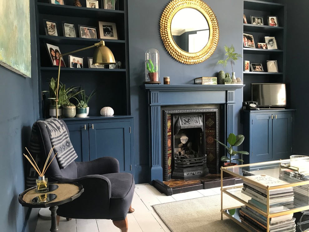 ロンドンにある低価格の小さなヴィクトリアン調のおしゃれな独立型リビング (青い壁、塗装フローリング、標準型暖炉、木材の暖炉まわり、白い床) の写真