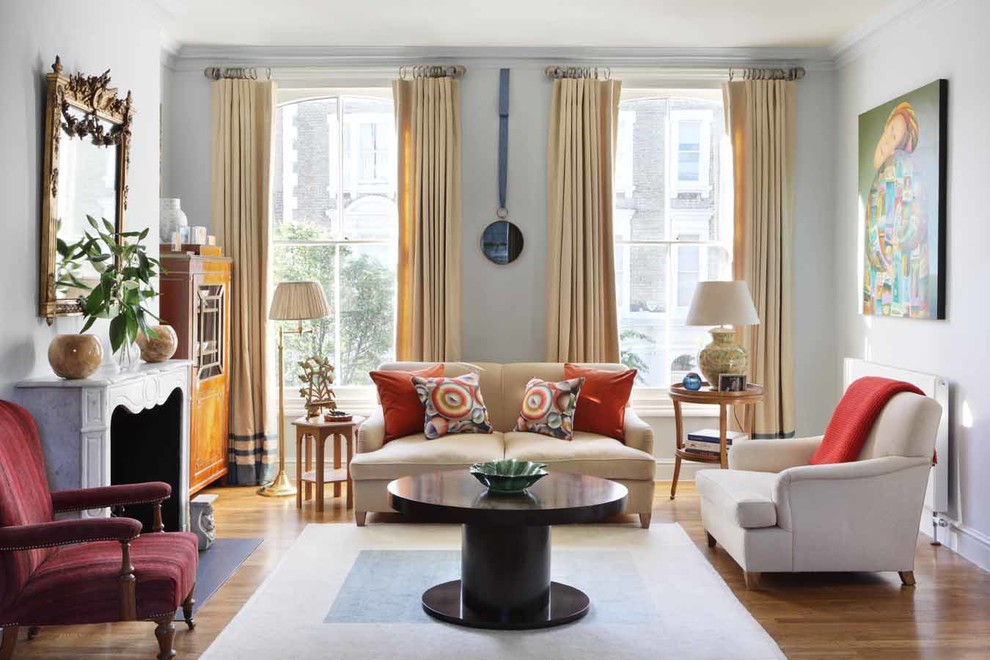 Fernseherloses, Offenes Klassisches Wohnzimmer mit Kamin, braunem Holzboden, blauer Wandfarbe und Kaminumrandung aus Stein in London