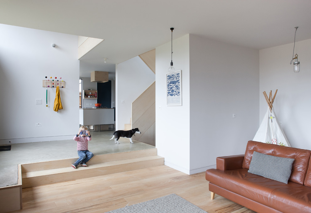 Bild på ett mellanstort minimalistiskt allrum med öppen planlösning, med vita väggar och ljust trägolv