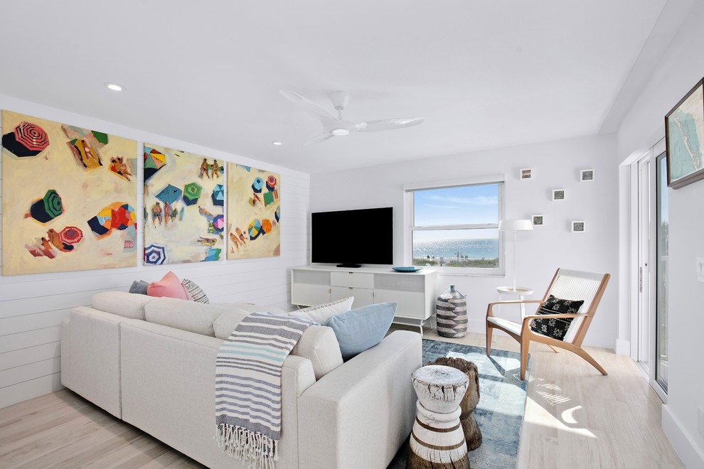 タンパにある低価格の小さなビーチスタイルのおしゃれなLDK (白い壁、セラミックタイルの床、壁掛け型テレビ、ベージュの床) の写真