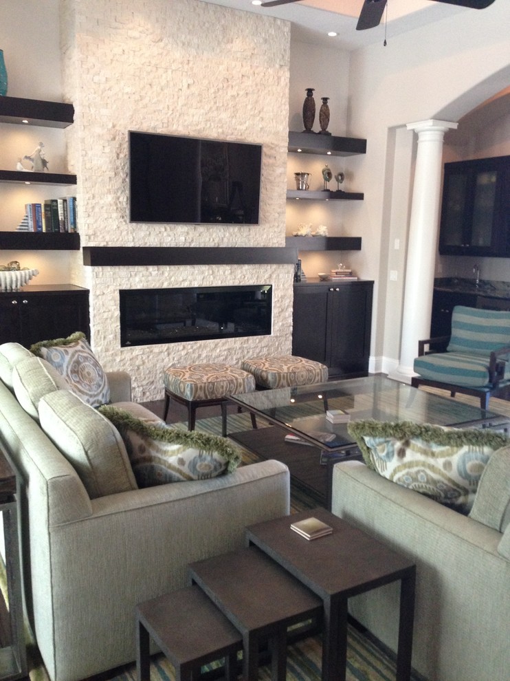 Mittelgroßes, Repräsentatives Klassisches Wohnzimmer mit beiger Wandfarbe, dunklem Holzboden, Kamin, Kaminumrandung aus Stein, TV-Wand und braunem Boden in Tampa