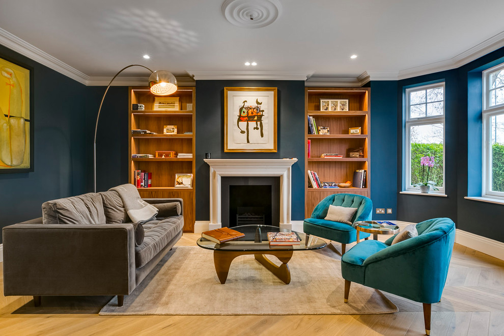 Идея дизайна: гостиная комната в стиле неоклассика (современная классика) с синими стенами, светлым паркетным полом и стандартным камином