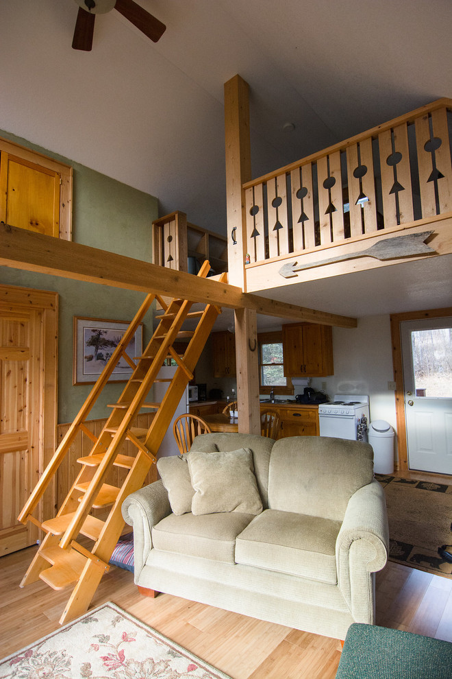 Cette image montre un petit salon chalet ouvert avec un mur vert, un sol en bois brun, un téléviseur indépendant et un sol marron.
