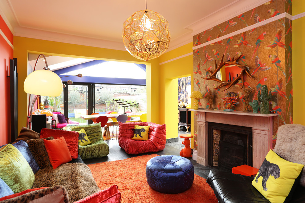 На фото: открытая гостиная комната среднего размера в стиле фьюжн с желтыми стенами, стандартным камином, фасадом камина из камня и черным полом