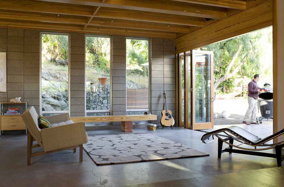 Imagen de salón abierto moderno de tamaño medio con paredes grises, suelo de cemento y suelo gris