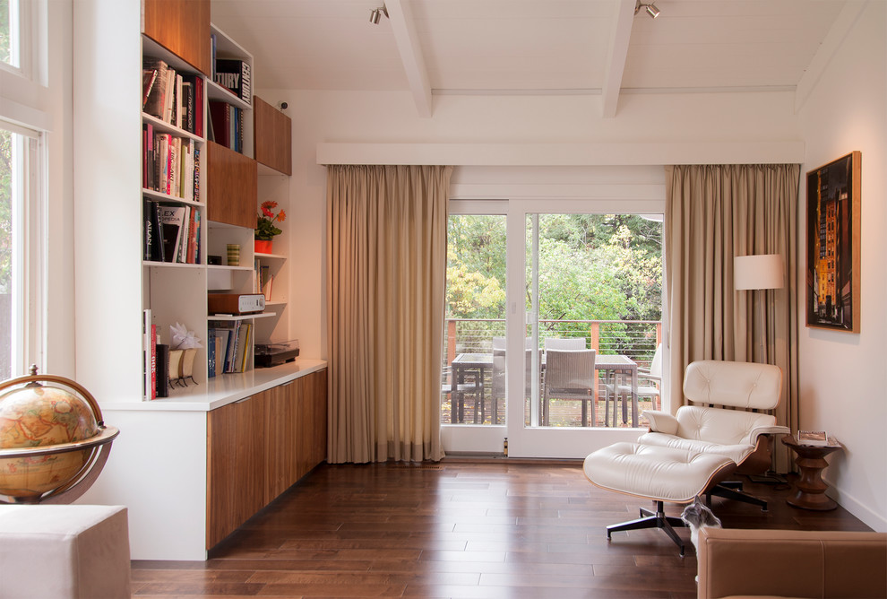 Idée de décoration pour un salon design de taille moyenne et ouvert avec une bibliothèque ou un coin lecture, un mur blanc, parquet foncé, aucun téléviseur et un sol marron.