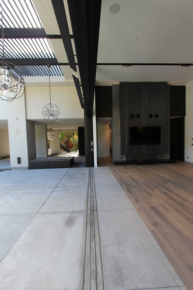 На фото: большая парадная, открытая гостиная комната в современном стиле с серыми стенами, светлым паркетным полом, телевизором на стене и серым полом без камина