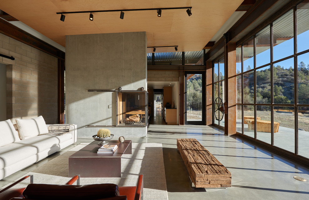Идея дизайна: открытая гостиная комната в стиле лофт с бетонным полом, угловым камином, фасадом камина из бетона и серым полом