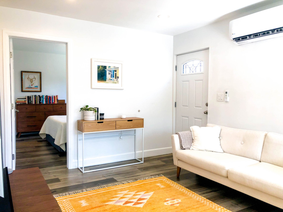 Идея дизайна: маленькая открытая гостиная комната в скандинавском стиле с паркетным полом среднего тона, коричневым полом, с книжными шкафами и полками, бежевыми стенами и телевизором на стене без камина для на участке и в саду