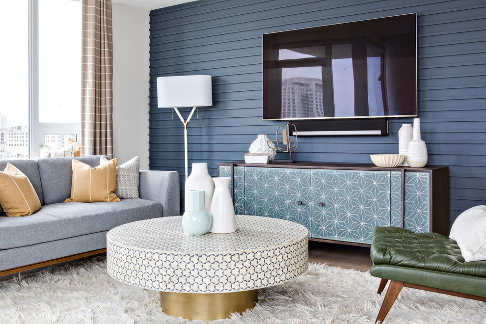 Cette image montre un grand salon vintage ouvert avec une salle de réception, un mur bleu, parquet clair, un téléviseur fixé au mur et un sol beige.