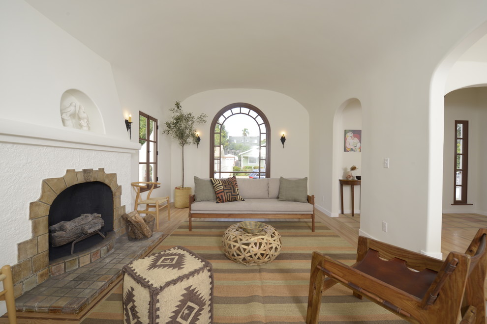 Diseño de salón para visitas abierto mediterráneo de tamaño medio con paredes blancas, suelo de madera clara, todas las chimeneas y marco de chimenea de baldosas y/o azulejos