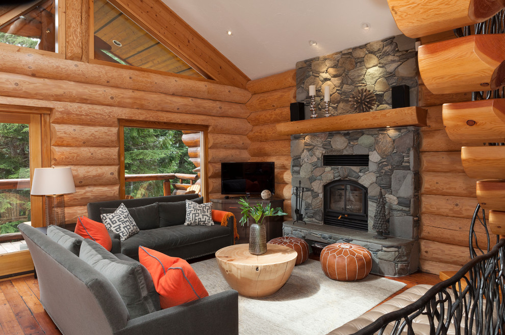 Inspiration pour un salon chalet ouvert avec un mur marron, un sol en bois brun, une cheminée standard, un manteau de cheminée en pierre, un téléviseur indépendant et un sol marron.