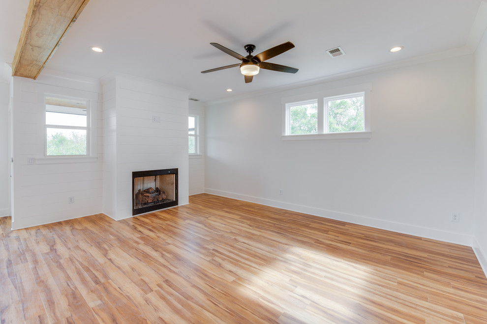 Example of a mid-sized farmhouse open concept light wood floor and beige floor living room design in Other with white walls, a standard fireplace and a wood fireplace surround