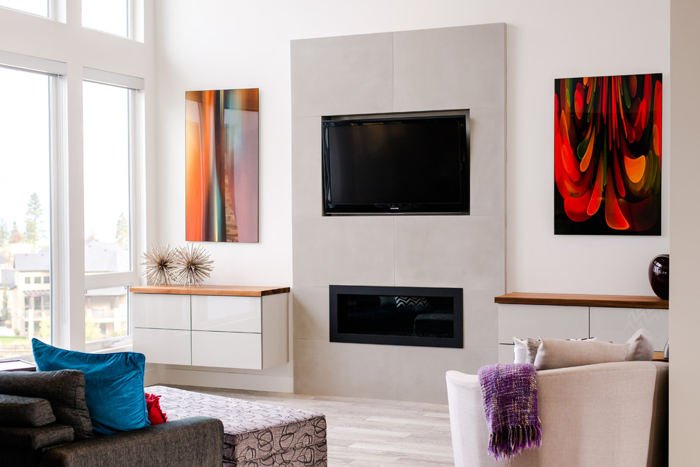 他の地域にあるお手頃価格の中くらいなモダンスタイルのおしゃれなLDK (白い壁、磁器タイルの床、標準型暖炉、コンクリートの暖炉まわり、壁掛け型テレビ、グレーの床) の写真
