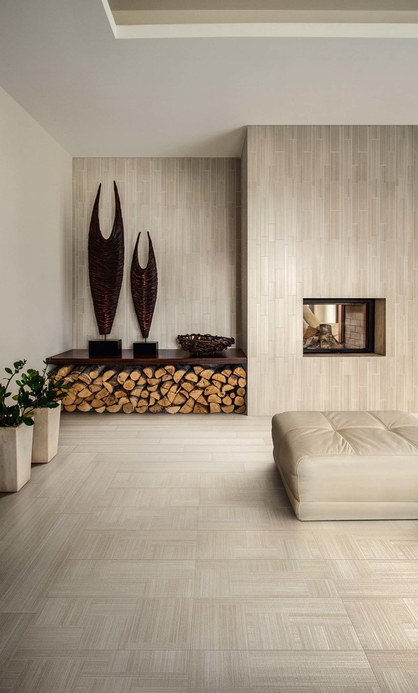Стильный дизайн: гостиная комната в стиле модернизм с полом из керамогранита, двусторонним камином, фасадом камина из плитки и бежевыми стенами - последний тренд