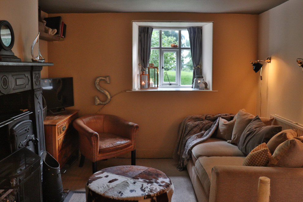 Exemple d'un petit salon chic fermé avec une bibliothèque ou un coin lecture, un mur beige, moquette, un poêle à bois, un manteau de cheminée en plâtre, un téléviseur d'angle et un sol beige.