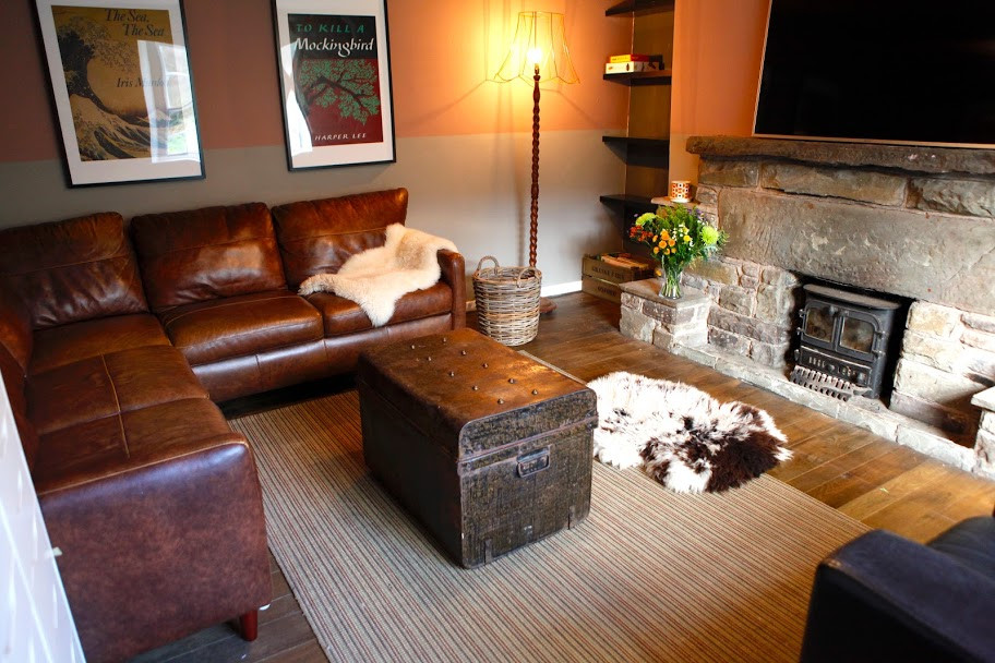 Foto di un soggiorno country con parquet scuro, stufa a legna, TV a parete e travi a vista