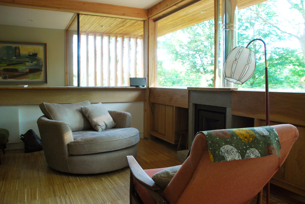 Esempio di un piccolo soggiorno country chiuso con libreria, pavimento in legno massello medio, cornice del camino in cemento e pareti verdi