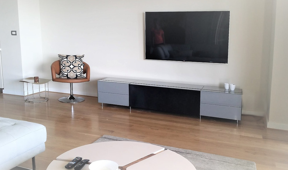 Immagine di un grande soggiorno moderno aperto con sala formale, pareti bianche, parquet chiaro e TV a parete