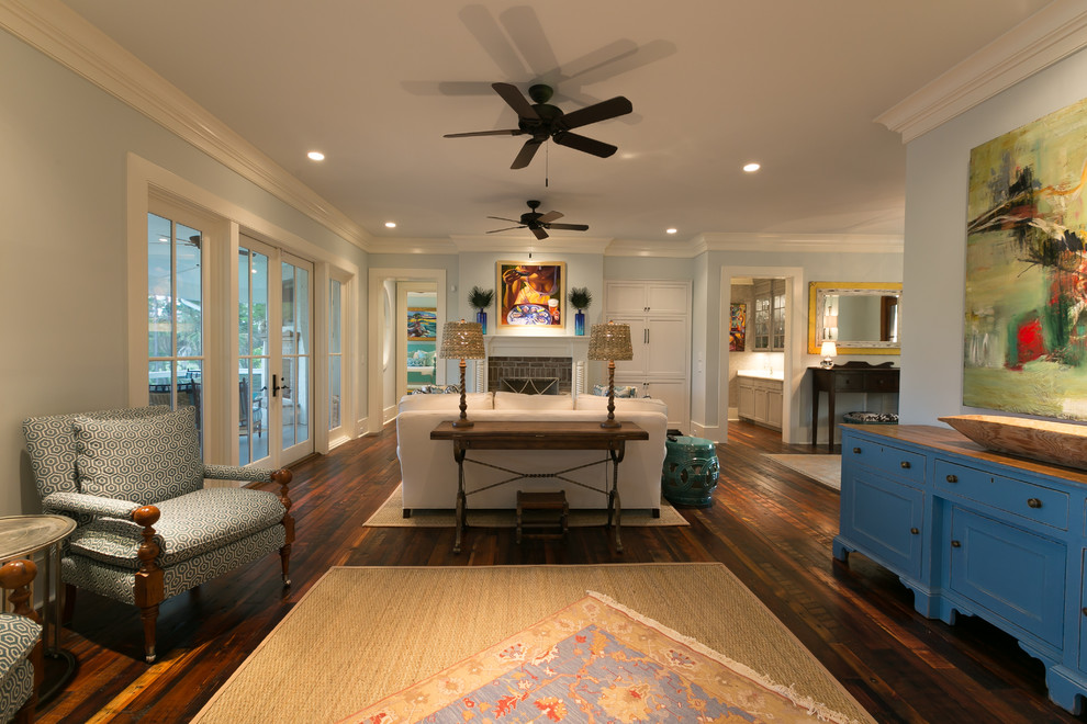 Offenes Klassisches Wohnzimmer mit blauer Wandfarbe, braunem Holzboden, Kamin und Kaminumrandung aus Backstein in Charleston
