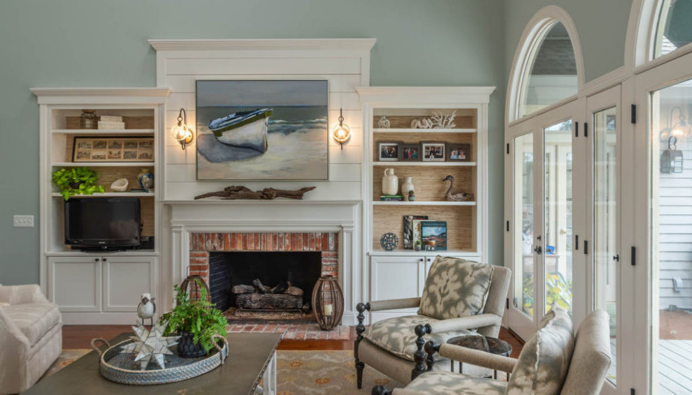 Photo of a nautical enclosed living room in Atlanta with a home bar, green walls, medium hardwood flooring, a standard fireplace, a brick fireplace surround, a freestanding tv and brown floors.