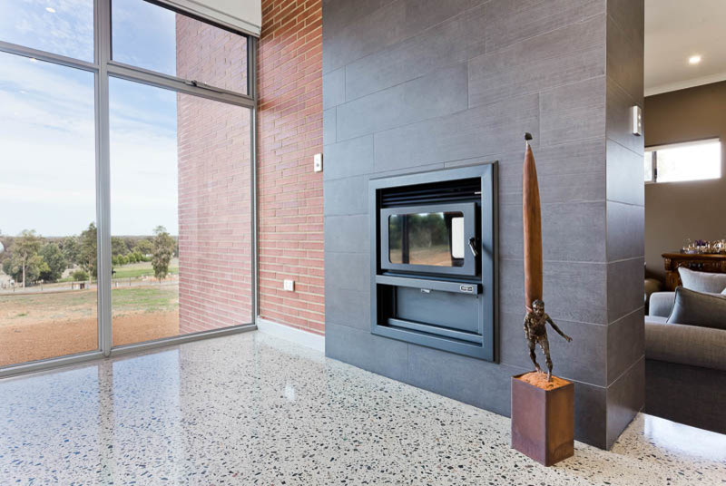 Ejemplo de salón minimalista con paredes blancas, suelo de cemento, todas las chimeneas, marco de chimenea de metal y suelo gris