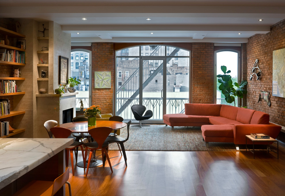 Aménagement d'un salon contemporain ouvert avec un sol en bois brun et un manteau de cheminée en pierre.