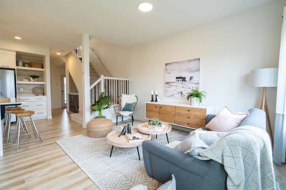 Modelo de salón abierto nórdico de tamaño medio sin chimenea y televisor con paredes blancas, suelo de madera clara y suelo beige