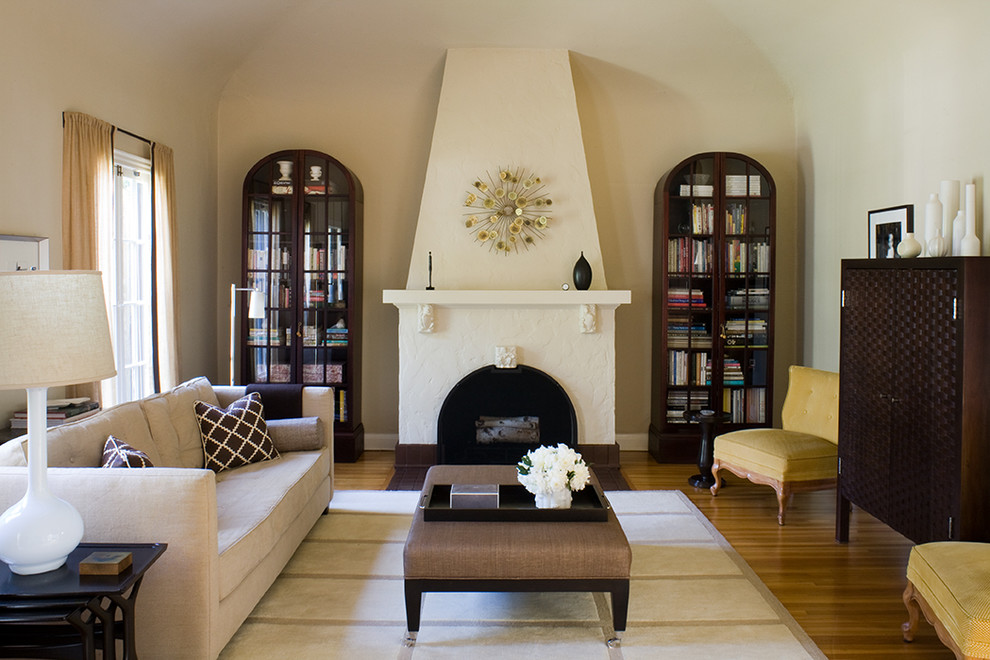 Mid-sized transitional enclosed light wood floor and brown floor living room photo in Los Angeles with beige walls, a standard fireplace, a plaster fireplace and no tv