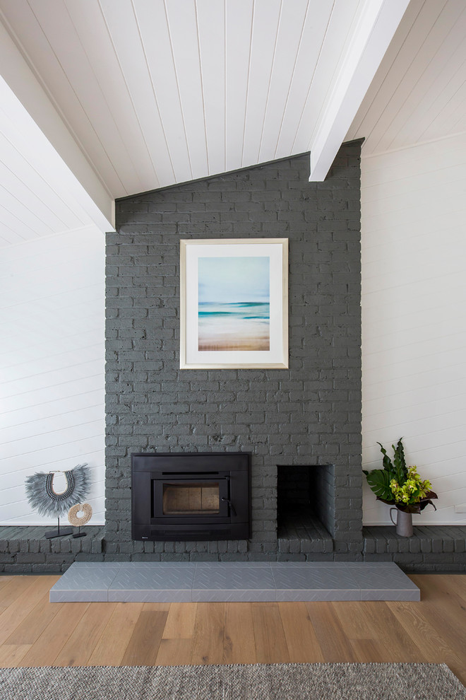 Réalisation d'un grand salon design ouvert avec un mur blanc, un sol en calcaire, une cheminée standard et un manteau de cheminée en brique.