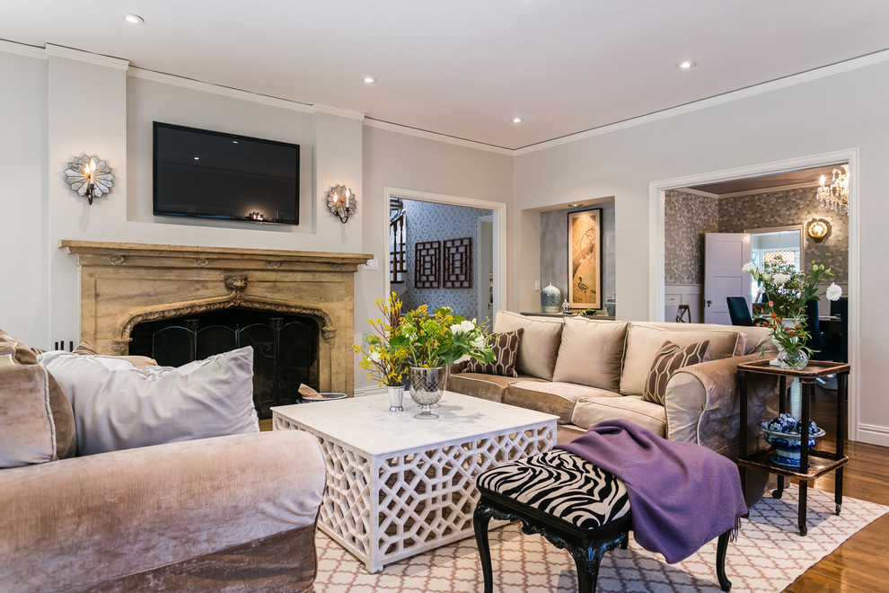 Источник вдохновения для домашнего уюта: гостиная комната в стиле неоклассика (современная классика) с серыми стенами, стандартным камином, фасадом камина из камня и телевизором на стене