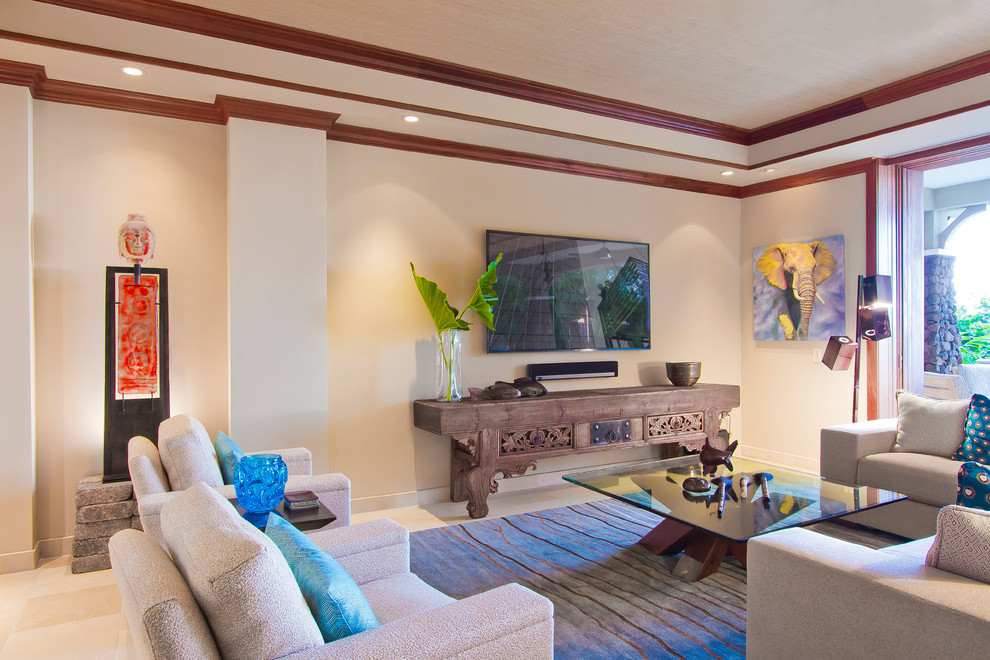 Esempio di un grande soggiorno tropicale aperto con pareti beige, pavimento in travertino, nessun camino e TV a parete