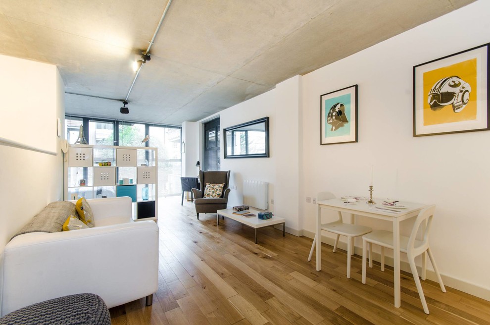 Exemple d'un petit salon tendance ouvert avec un mur blanc et un sol en bois brun.
