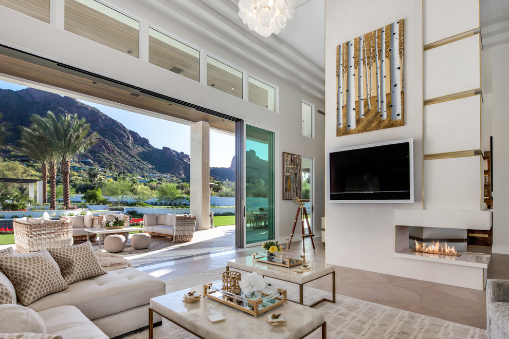 Design ideas for an expansive contemporary open plan living room in Phoenix with a home bar, white walls, light hardwood flooring, a two-sided fireplace, a stone fireplace surround, a wall mounted tv and brown floors.