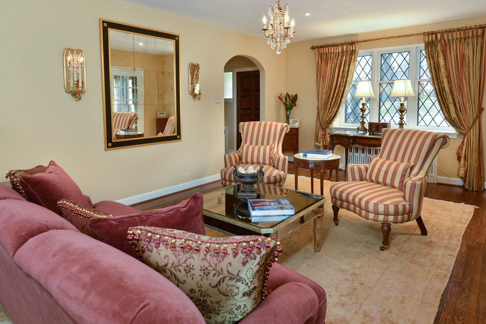 Cette photo montre un grand salon chic avec une salle de réception, un mur beige, un sol en bois brun et un manteau de cheminée en pierre.