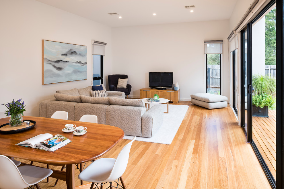 Mittelgroßes, Offenes Modernes Wohnzimmer ohne Kamin mit beiger Wandfarbe, hellem Holzboden und freistehendem TV in Melbourne