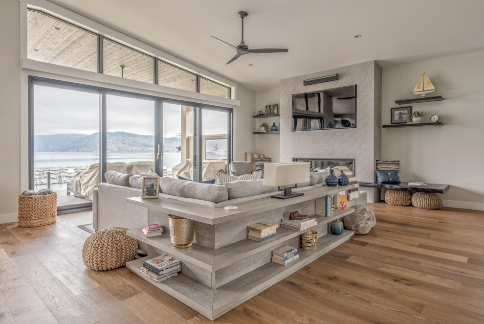 Immagine di un soggiorno stile marinaro aperto con pareti grigie, pavimento in legno massello medio, TV a parete e pavimento marrone