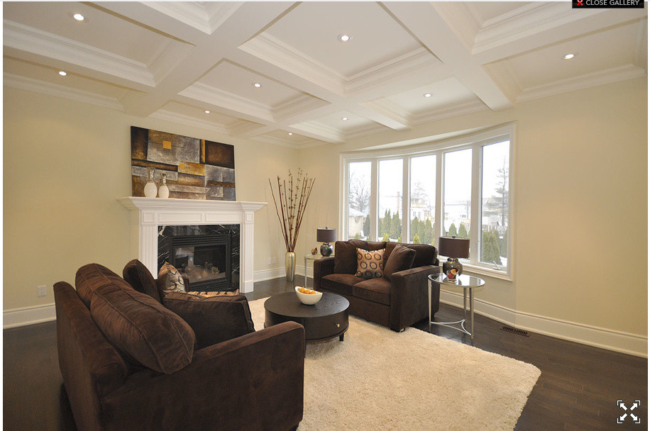 Mittelgroßes, Repräsentatives, Fernseherloses, Abgetrenntes Modernes Wohnzimmer mit beiger Wandfarbe, dunklem Holzboden, Kamin und Kaminumrandung aus Holz in Toronto