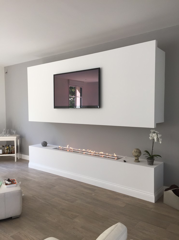 This is an example of a contemporary living room in Sussex with a ribbon fireplace.