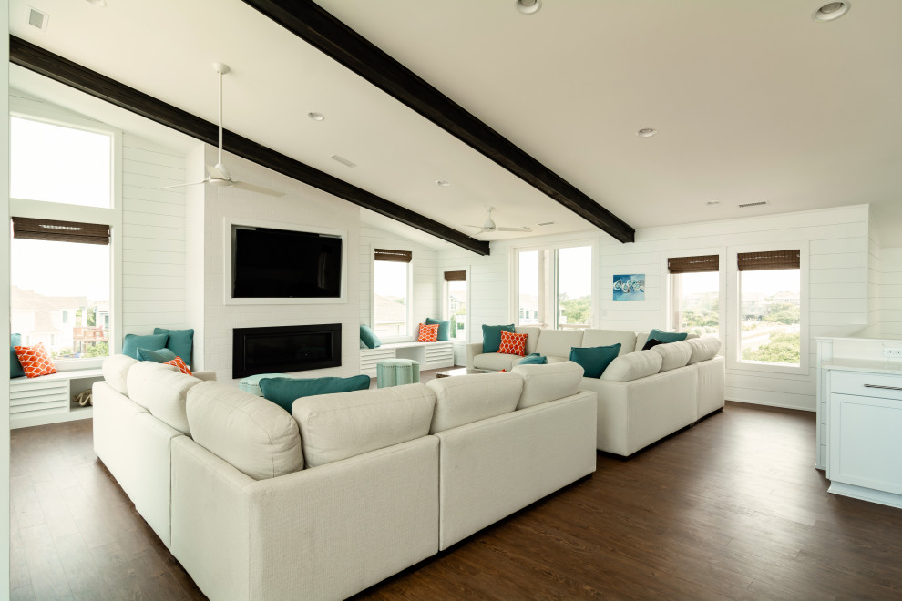 Photo of an expansive coastal open plan living room in Other with white walls, medium hardwood flooring, a ribbon fireplace, a brick fireplace surround, a wall mounted tv and brown floors.