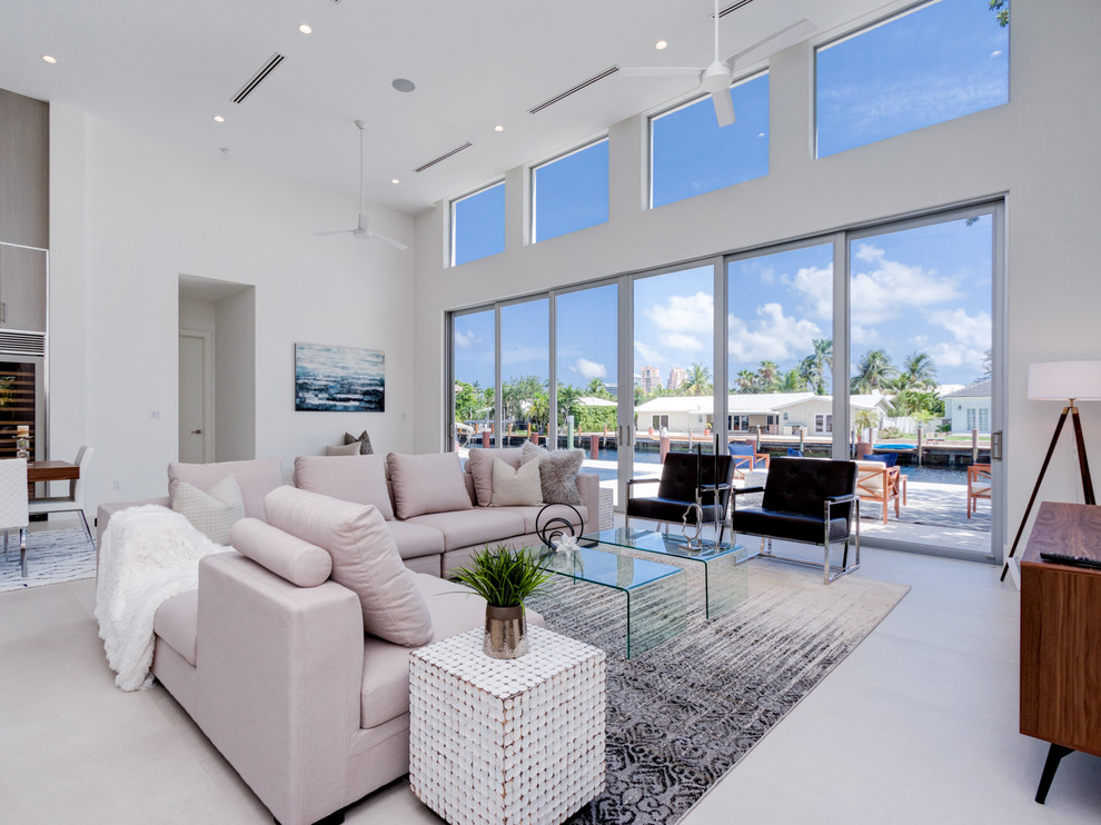 This is an example of a medium sized nautical formal open plan living room in Miami with white walls, concrete flooring, no fireplace, a wall mounted tv and grey floors.
