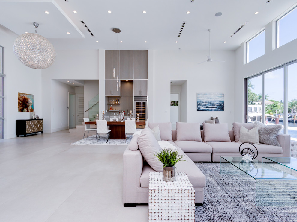Example of a mid-sized beach style formal and open concept concrete floor and gray floor living room design in Miami with white walls, no fireplace and a wall-mounted tv